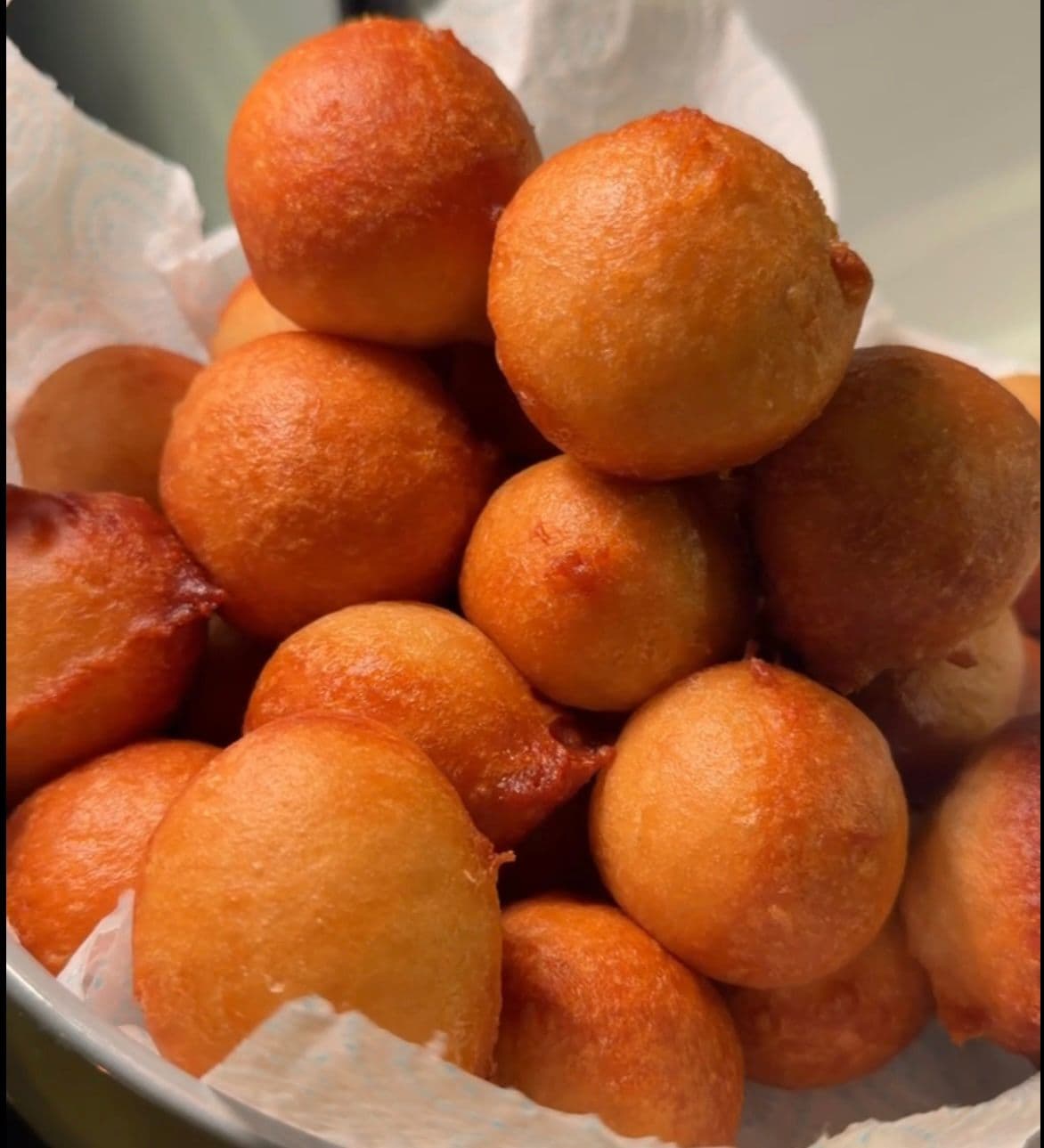 Golden, glossy puff puff piled in a bowl
